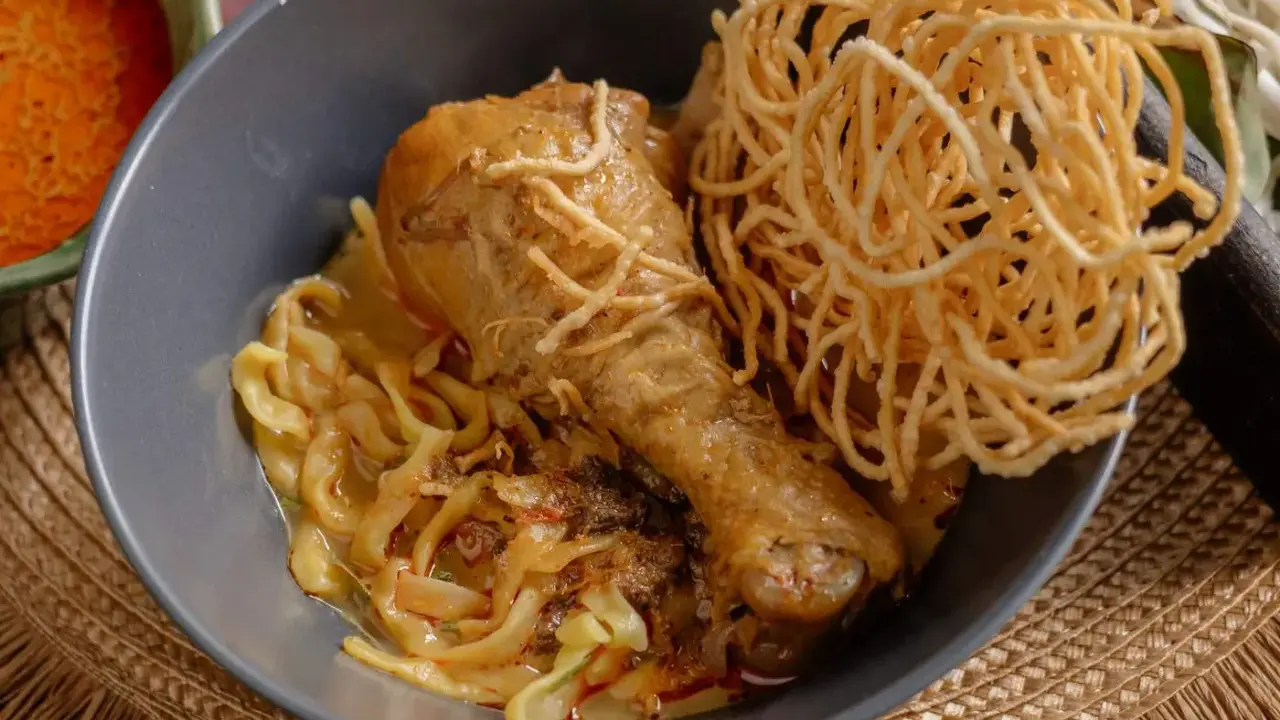 Khao Soi: Hühnerkeule in cremiger Kokosmilch-Currysauce mit weichen und knusprigen Nudeln.