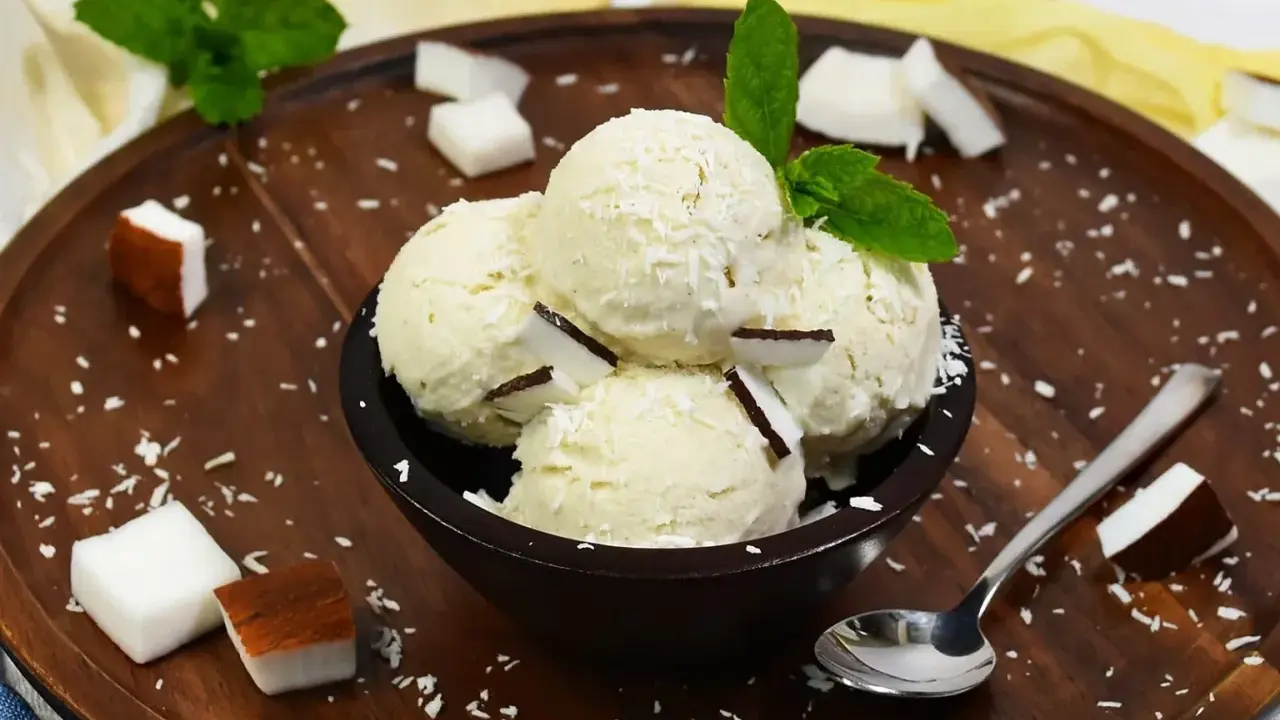 Schüssel mit cremigem Kokoseis, garniert mit Kokosraspeln und Minze. Perfekt, um Kokoseis selber zu machen!