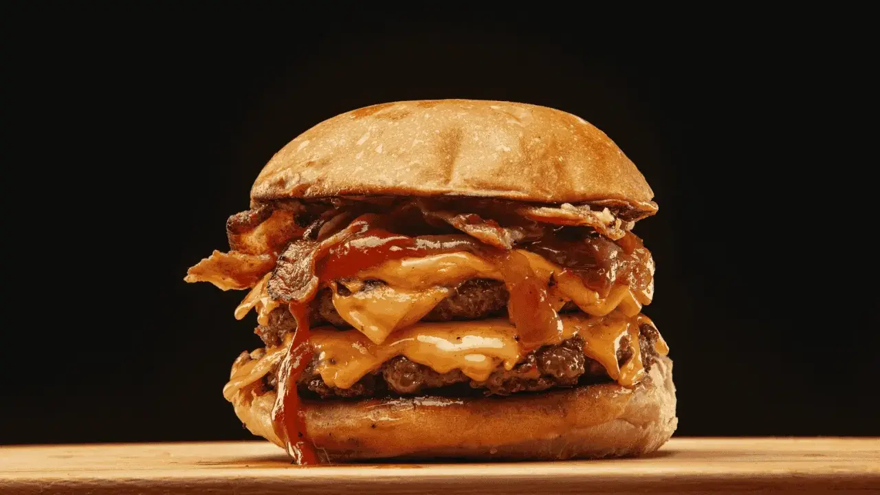 Ein saftiger Burger zubereiten: Doppelt Fleisch, geschmolzener Käse, knuspriger Bacon und eine köstliche Sauce.