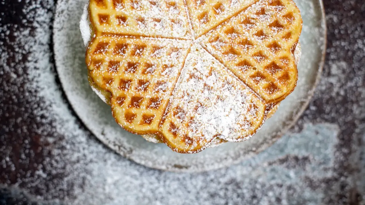 Herzförmige Waffeln mit Puderzucker bestreut, serviert auf einem Teller. Ein Genuss, der an Sommer und Kokosmilch erinnert.