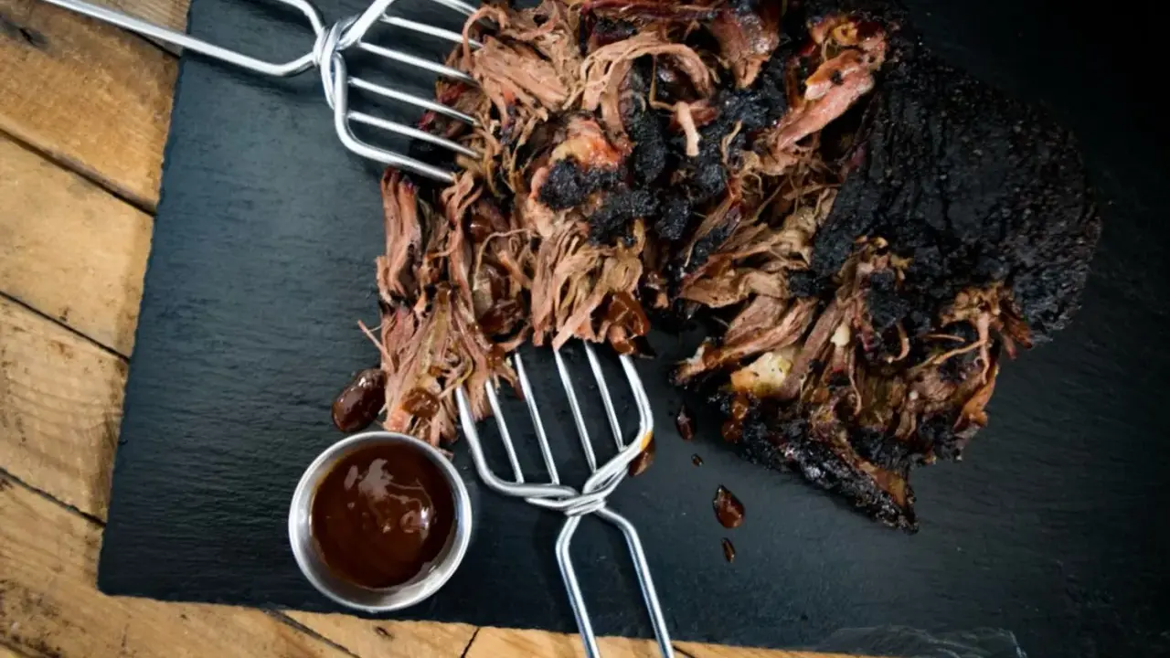 Saftiges pulled beef mit dunkler Kruste, serviert mit BBQ-Sauce.