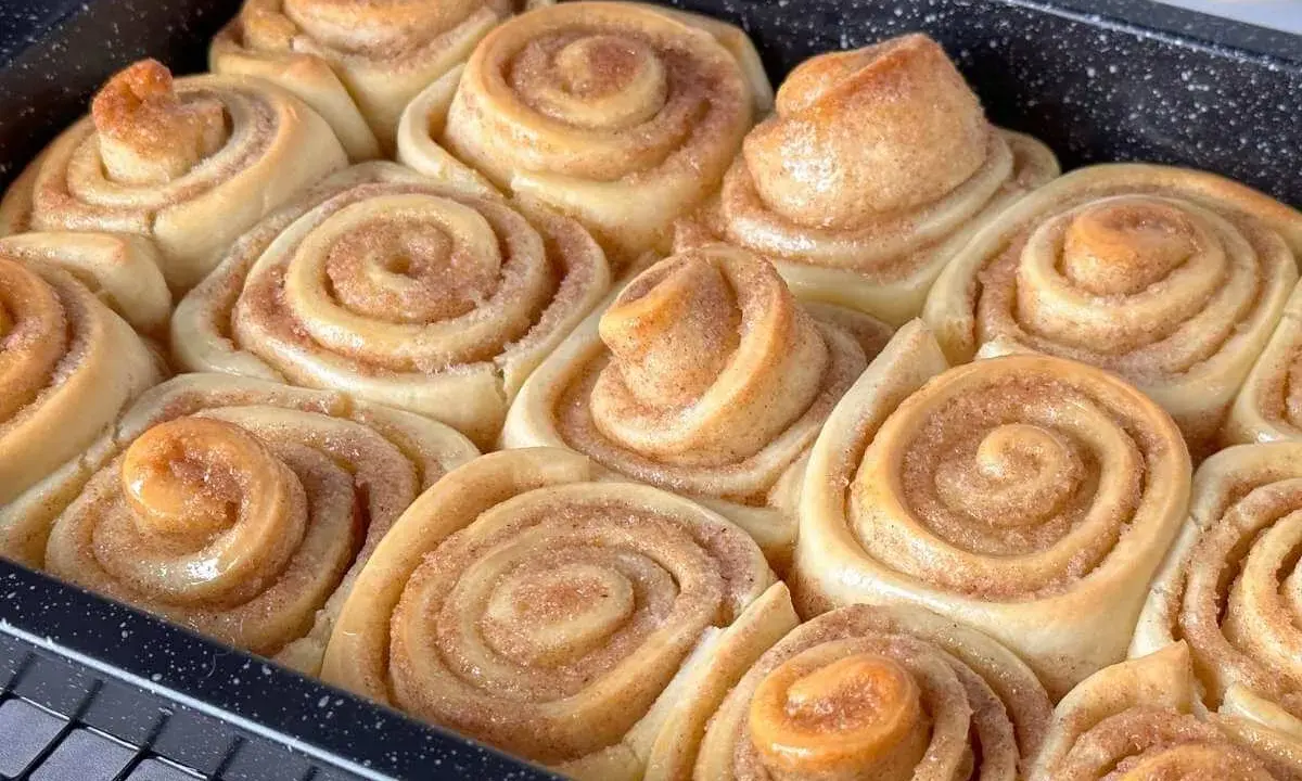 Frisch gebackene, fluffige Zimtschnecken in einer Backform. Sie duften nach Zimt und Zucker und sind bereit zum Genießen.