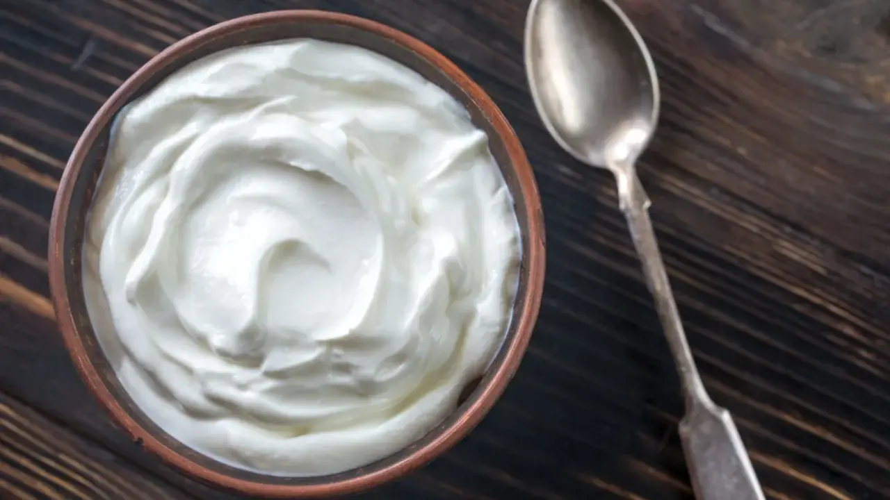 Schüssel mit cremiger Joghurt-Textur, eine tolle Alternative, wenn man fragt, was kann man statt Creme Fraiche nehmen. Daneben eine Löffel.