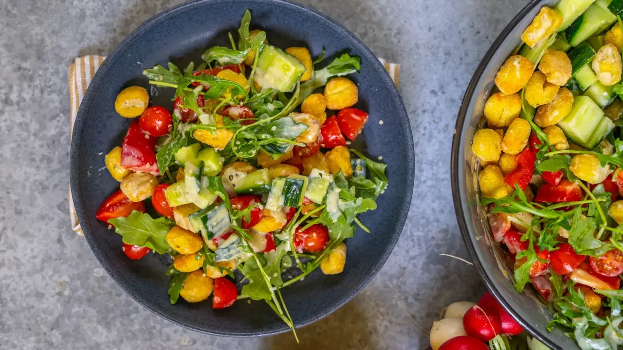 Knuspriger Gnocchi Salat aus dem Airfryer mit Tomaten, Gurken und Rucola, verfeinert mit einem cremigen Dressing.