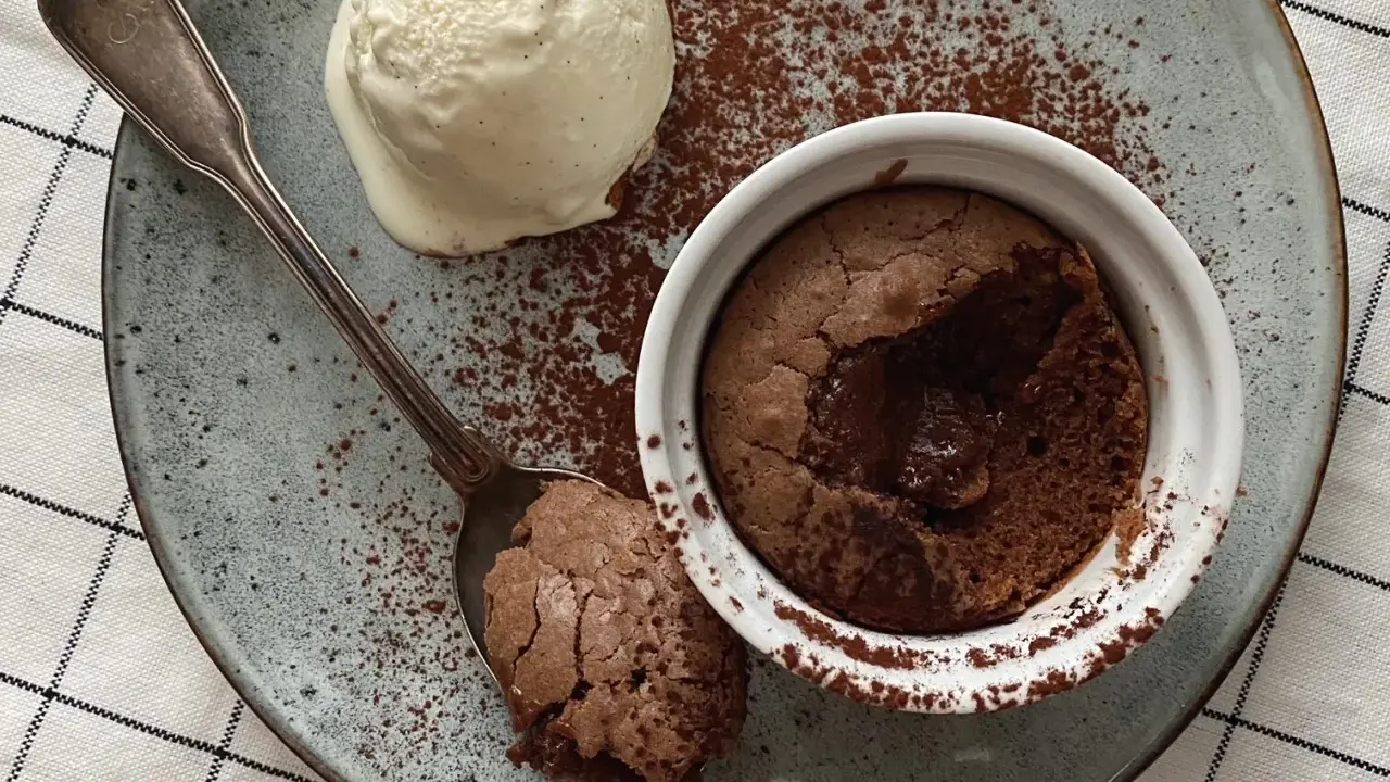 Ein warmer, flüssiger Kern im Moelleux au chocolat, serviert mit einer Kugel Vanilleeis und Kakaopulver.