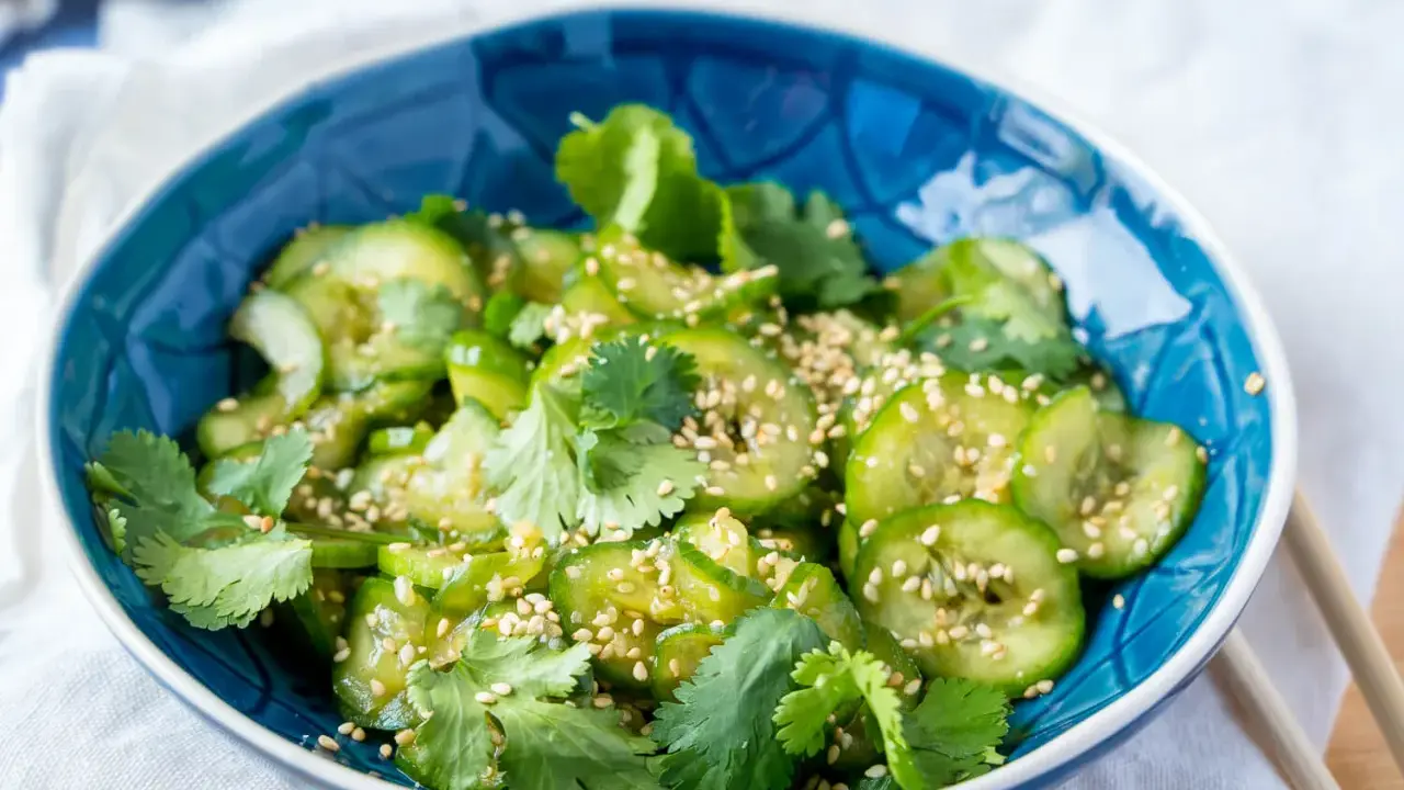 Erfrischender Gurkensalat asiatisch, garniert mit Koriander und Sesam. Perfekt als leichte Beilage.