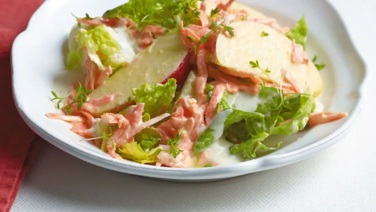 Erfrischender karotten apfel-salat mit joghurt und knackigem Salat, garniert mit Kresse.