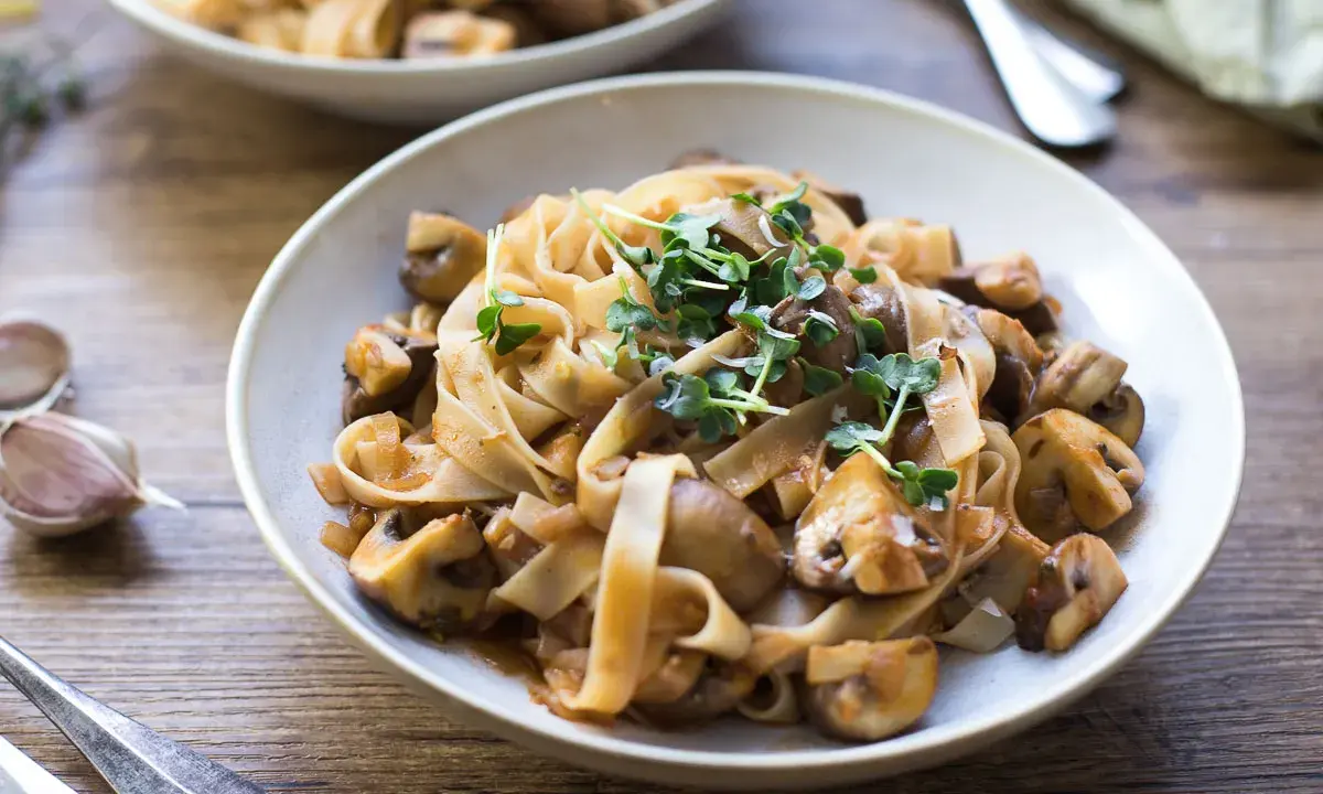 Herzhafte Pasta mit Pilzsauce, ein italienischer Genuss, garniert mit frischen Sprossen.