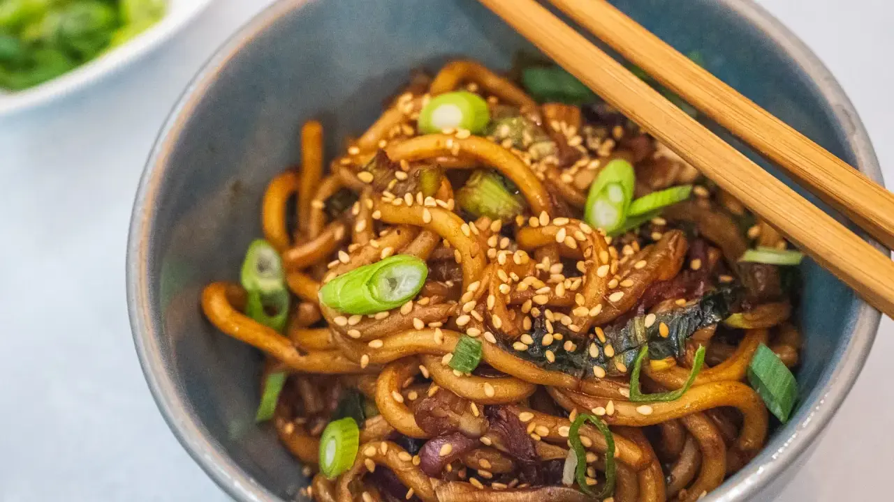 Schüssel mit Udon-Nudeln, garniert mit Frühlingszwiebeln und Sesam. Diese dicken, zähen Nudeln sind ein Klassiker der japanischen Küche.