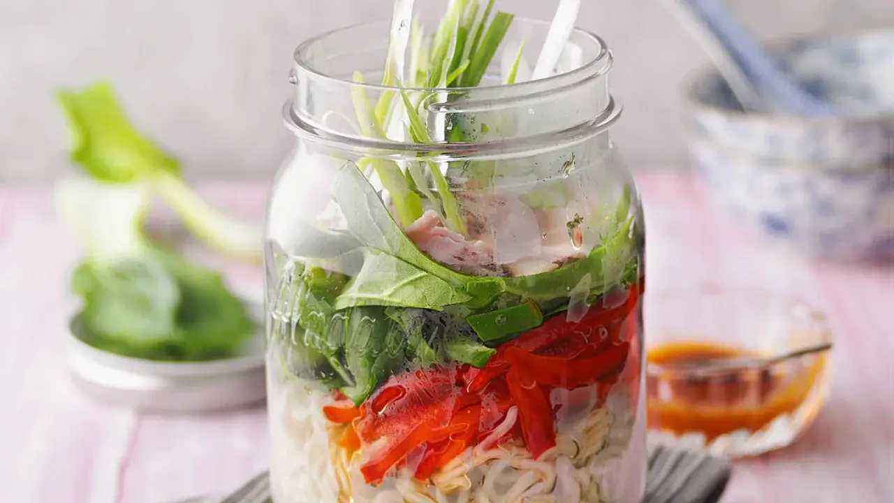 Eine köstliche pak choi suppe in einem Glas, geschichtet mit Nudeln, Gemüse und Fleisch.