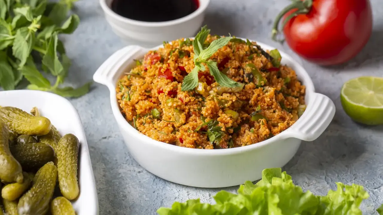 Frischer Bulgursalat mit Tomaten, Kräutern und Minze, serviert mit Gurken und Limette. Das beste bulgursalat rezept für einen leichten Genuss.