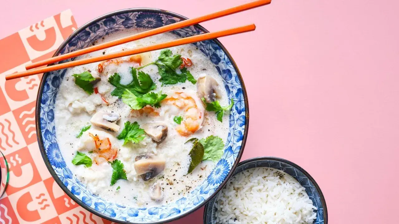 Khao tom, eine cremige Reissuppe mit Garnelen, Pilzen und Koriander, wird mit einem Schälchen Reis serviert.