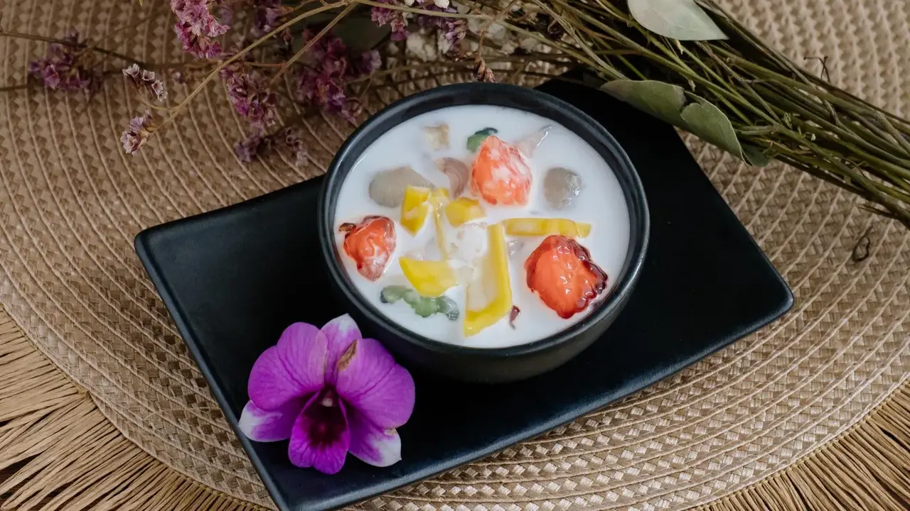 Schüssel mit cremigen asiatischen Nachspeisen, garniert mit Früchten und einer Orchidee.