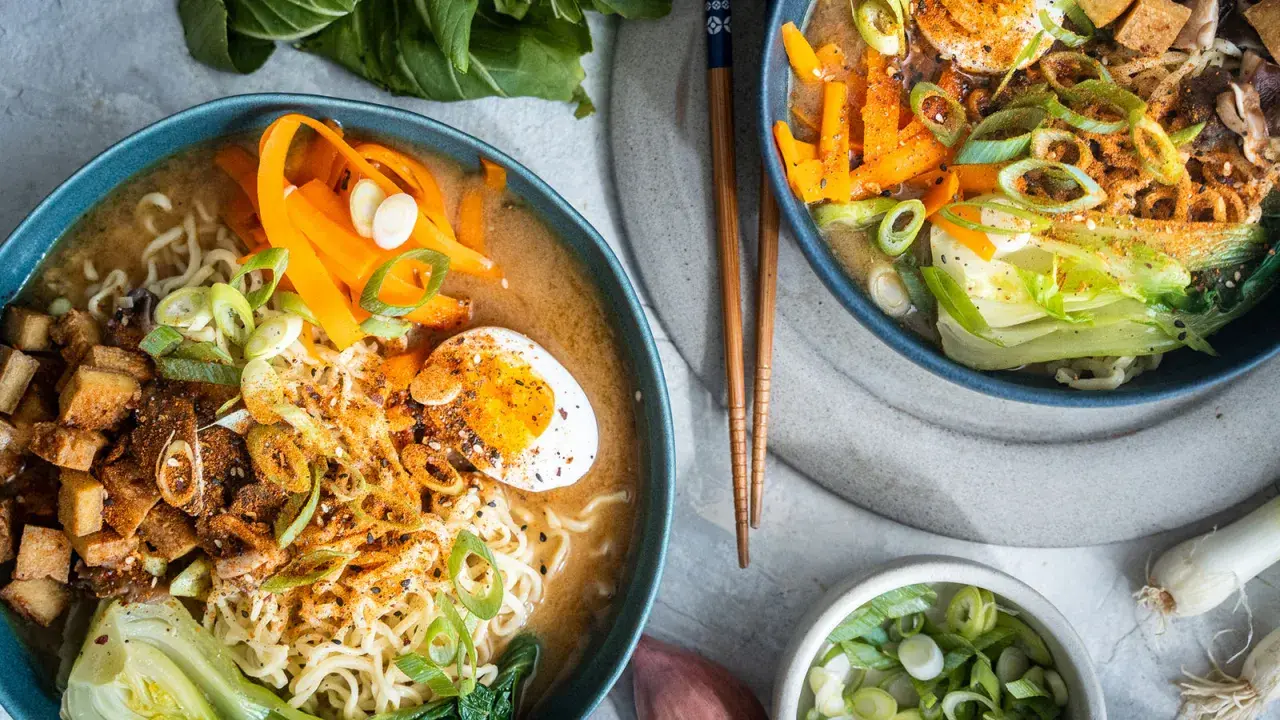 Zwei Schüsseln Miso Ramen mit Rindfleisch, Nudeln, Ei, Karotten und Frühlingszwiebeln.