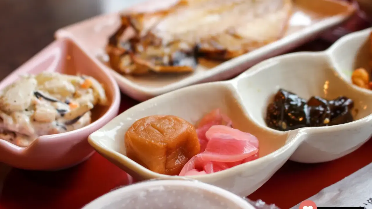 Ein traditionelles japanisches Frühstück mit gegrilltem Fisch, eingelegtem Gemüse und einer cremigen Beilage.