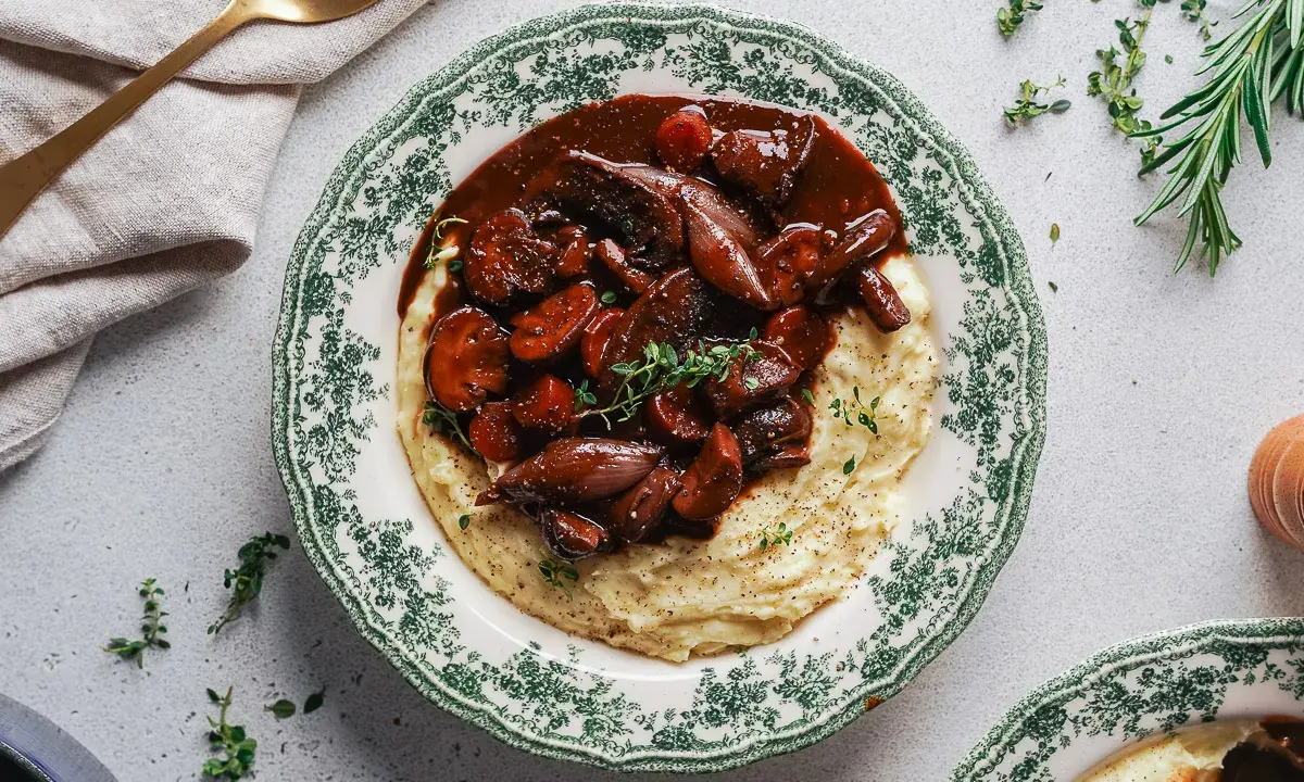 Herzhaftes Pilz-Bourguignon auf cremigem Kartoffelpüree, garniert mit frischen Kräutern. Ein Genuss für jeden Gaumen.