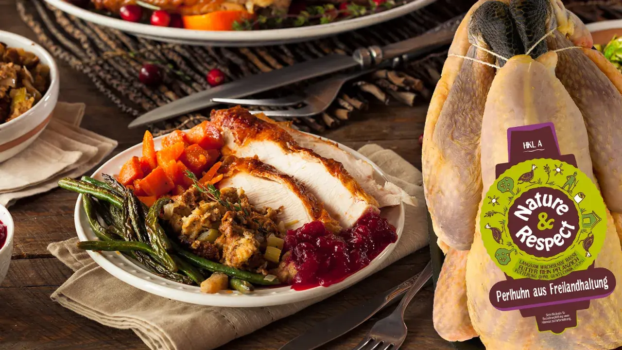 Ein festlich gedeckter Tisch mit einem Teller voller gebratenem Perlhuhn, dazu grüne Bohnen, Karotten und Cranberry-Sauce. Das unzubereitete Perlhuhn daneben zeigt das Label "Nature & Respect".