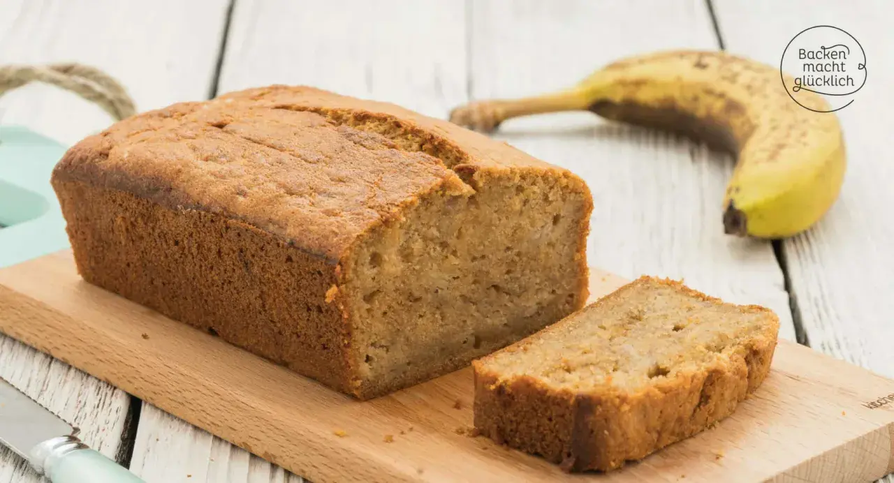 Saftiges Bananenbrot mit Skyr, frisch gebacken und auf einem Holzbrett angerichtet. Eine Banane liegt daneben.