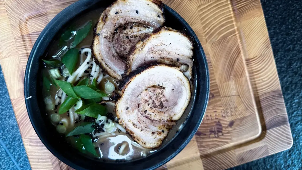 Schüssel mit Ramen-Nudeln, Brühe, Frühlingszwiebeln und drei Scheiben Chashu-Schweinebauch. Ein köstliches Chashu-Rezept!