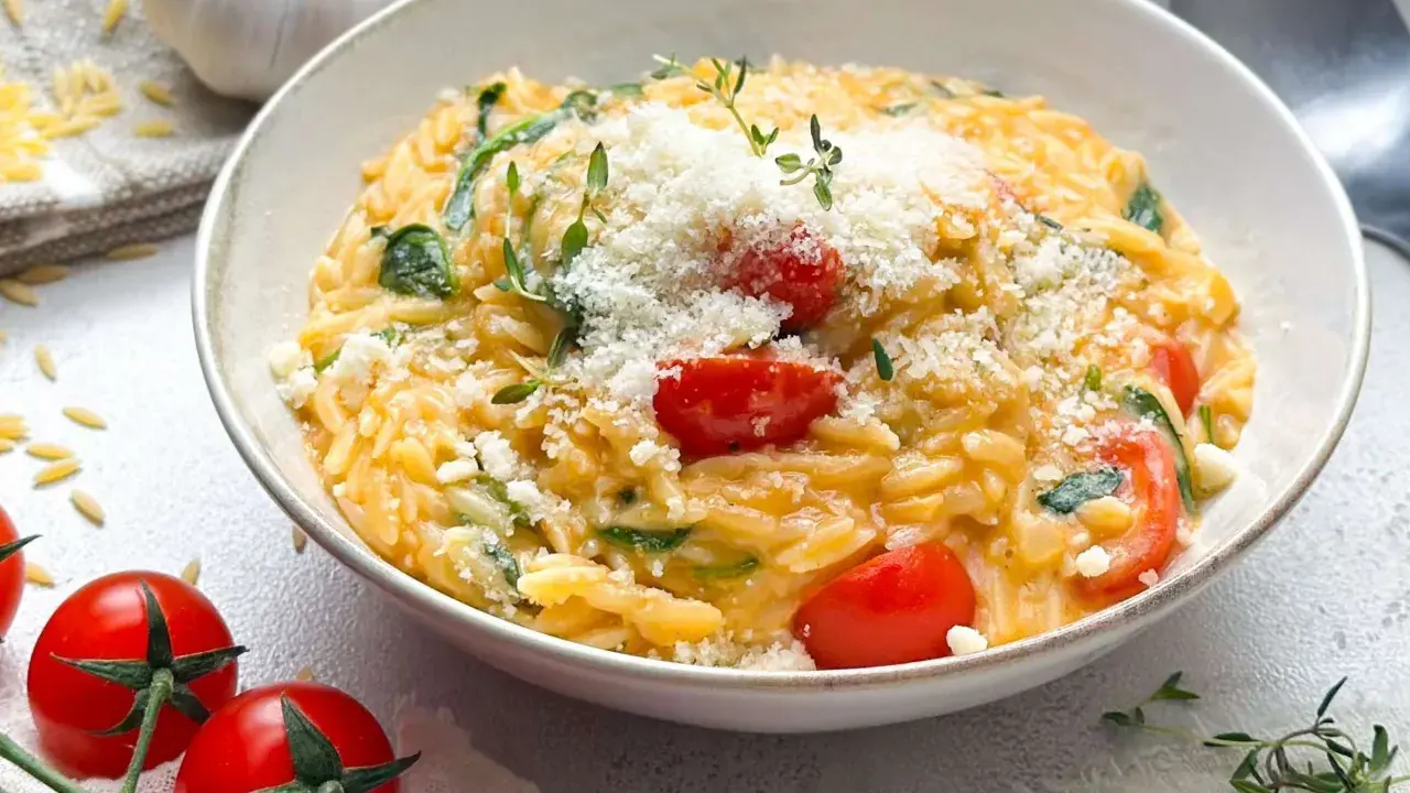 Cremiges One Pot Orzo mit Kirschtomaten, Spinat und Parmesan, garniert mit frischem Thymian.