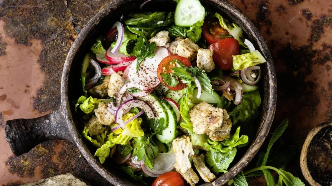 Frischer Fattoush Salat mit knackigem Gemüse, geröstetem Brot und Kräutern in einer rustikalen Schale. Ein tolles Fattoush Rezept!