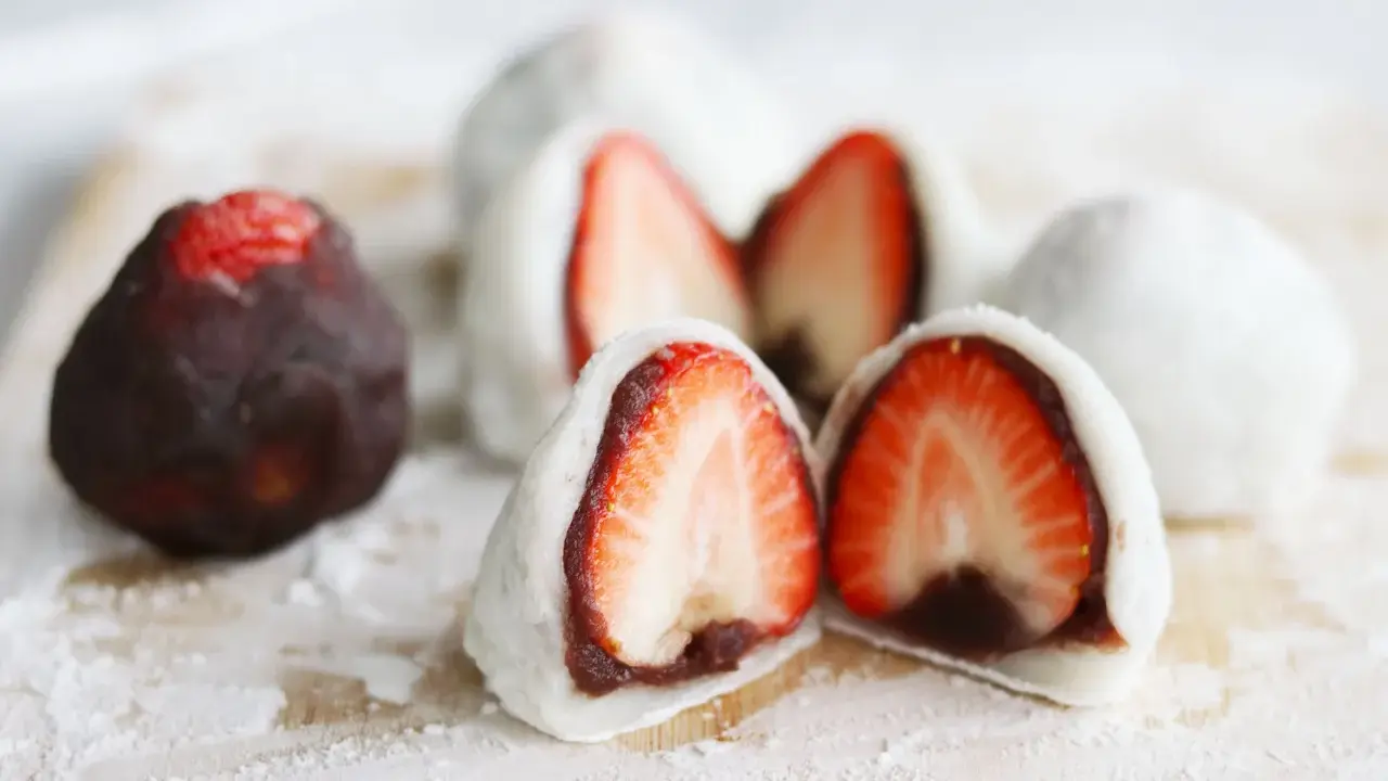 Erdbeeren-Wagashi-Rezept: Süße Mochi-Bällchen mit frischen Erdbeeren und roter Bohnenpaste, bestäubt mit Puderzucker.