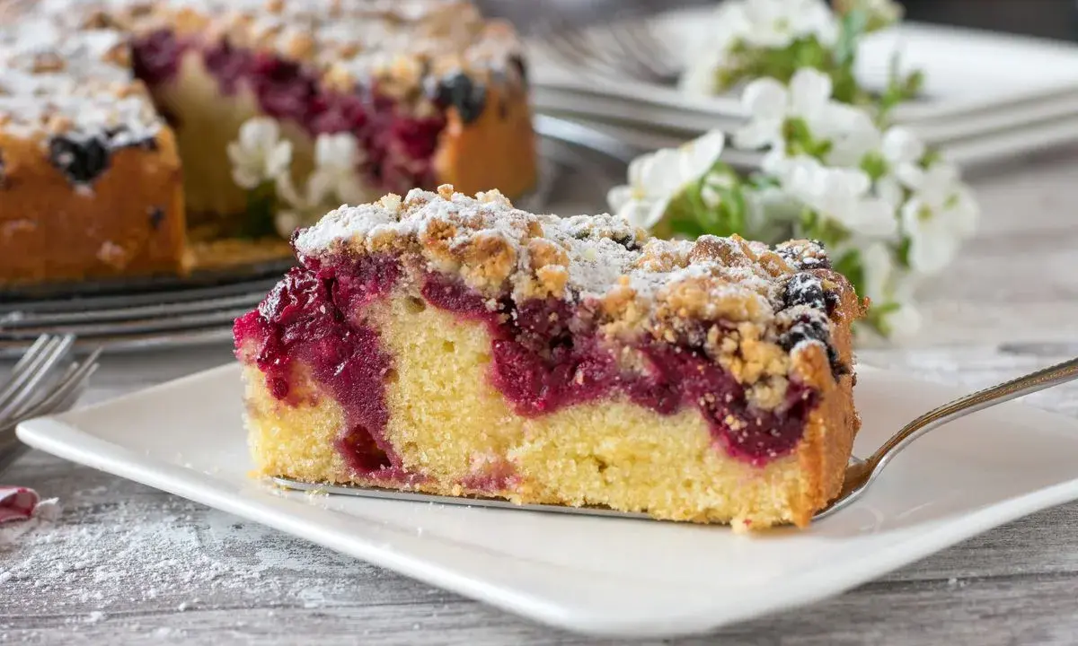 Ein saftiges Stück Streuselkuchen mit Marmelade und Puderzucker bestreut, bereit zum Genuss.