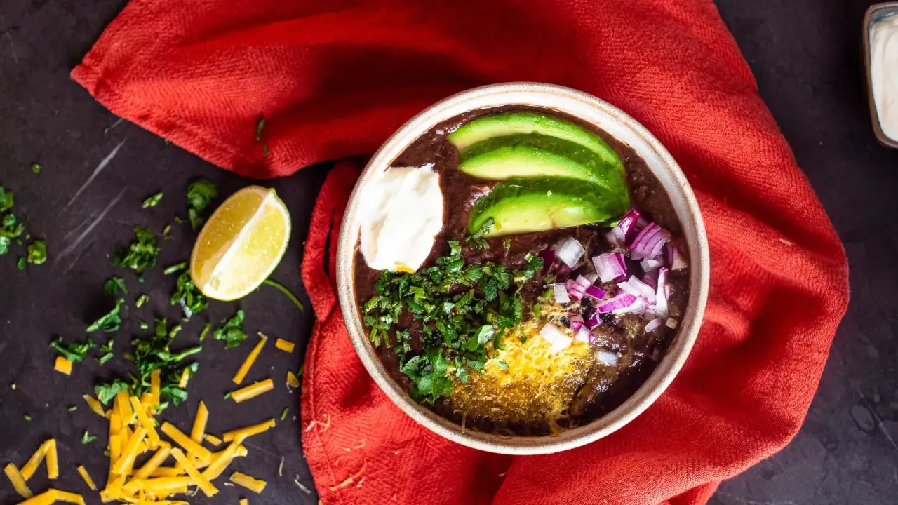 Herzhafter schwarze bohnen eintopf mit Avocado, Sauerrahm, Zwiebeln und Koriander. Ein Genuss für kalte Tage.