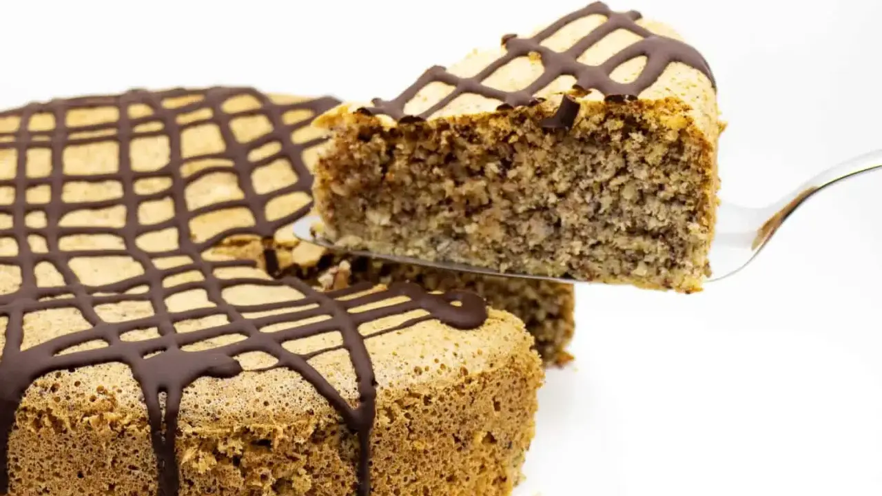 Ein Stück zuckerfreier Kuchen mit Schokoladenglasur wird aus einem Ganzen gehoben.