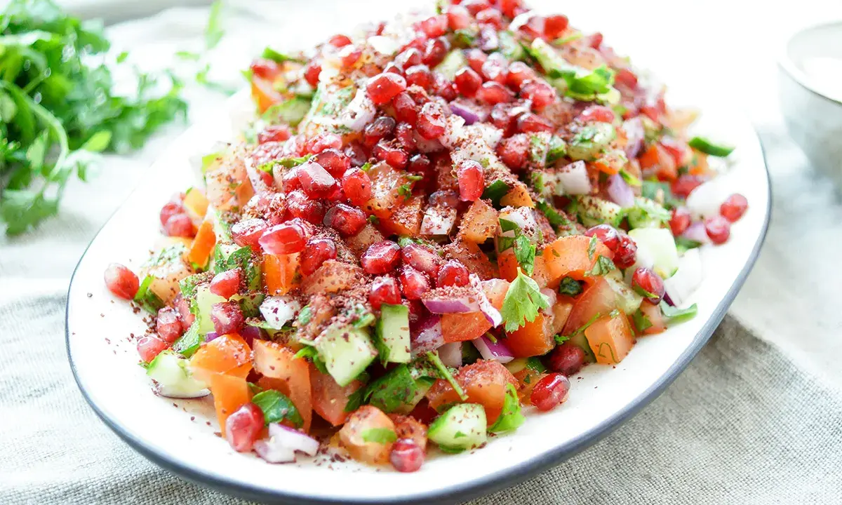 Frischer persischer Salat mit Granatapfel, Tomaten, Gurken und Kräutern, bestreut mit Sumach.