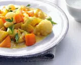 Ein Teller mit cremigem Curry-Eintopf, gefüllt mit Kartoffeln, Karotten und Lauch, garniert mit Petersilie.