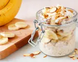 Gesunder Porridge mit Banane, Nüssen und Kokosraspeln im Glas. Perfekt für einen energiegeladenen Start in den Tag.