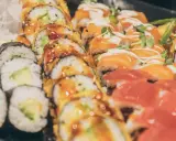 Vielfalt an Sushi-Rollen mit Lachs, Avocado und frischen Kräutern. Eine Frage, wie gesund ist Sushi, lässt sich hier nicht pauschal beantworten.