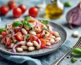 Ein frischer weisse bohnen salat mit Tomaten, roten Zwiebeln und Basilikum, garniert mit Olivenöl und Gewürzen.