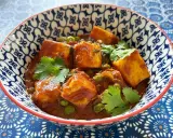 Schüssel mit cremigem Mattar Paneer, garniert mit Koriander. Die Sauce ist reichhaltig und rotbraun, mit Erbsen und würzigen Paneer-Würfeln.