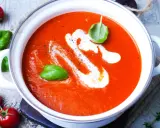 Eine cremige, beste Tomatensuppe mit Basilikum und einem Swirl Sahne, garniert mit frischen Tomaten und Kräutern.