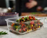 Frischer schwarze bohnen salat mit Mais, Tomaten und Kräutern in einer Glasbox, bereit zum Mitnehmen.