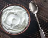 Schüssel mit cremiger Joghurt-Textur, eine tolle Alternative, wenn man fragt, was kann man statt Creme Fraiche nehmen. Daneben eine Löffel.