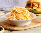 Schüssel mit cremigem Coleslaw, perfekt für das **rezept coleslaw original**. Im Hintergrund ein Burger.