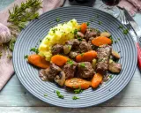 Herzhaftes Boeuf Bourguignon Rezept mit zartem Rindfleisch, Karotten, Pilzen und Kartoffelpüree, garniert mit Petersilie.