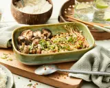 Schüssel mit gebratenen asiatischen Pilzen, garniert mit Frühlingszwiebeln und Koriander, daneben Reis und Chilis.