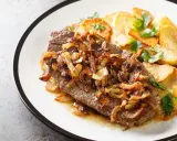 Ein saftiges Stück Rindfleisch, bedeckt mit goldbraunen Röstzwiebeln, serviert mit knusprigen Bratkartoffeln. Das ist der beste Zwiebelrostbraten!