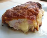 Ein goldbraunes Cordon Bleu, das innen mit geschmolzenem Käse und Schinken gefüllt ist. Seine Herkunft ist oft umstritten, aber der Geschmack ist unbestritten.