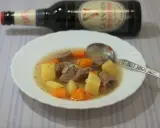 Herzhafter Irish Stew mit Kartoffeln und Karotten in einer Schüssel, daneben eine Flasche Guinness.
