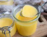 Ein Löffel Butterschmalz wird aus einem Glas gehoben. Dieses goldgelbe Fett ist ideal zum Braten, da sein hoher Butterschmalz rauchpunkt Verbrennungen verhindert.