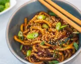 Schüssel mit Udon-Nudeln, garniert mit Frühlingszwiebeln und Sesam. Diese dicken, zähen Nudeln sind ein Klassiker der japanischen Küche.