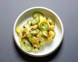 Kartoffelsalat mit frischer Gurke, garniert mit lila Sprossen und Dill. Ein leichter und erfrischender Genuss.