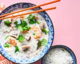 Khao tom, eine cremige Reissuppe mit Garnelen, Pilzen und Koriander, wird mit einem Schälchen Reis serviert.