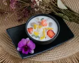 Schüssel mit cremigen asiatischen Nachspeisen, garniert mit Früchten und einer Orchidee.