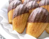Eine Reihe von Madeleines, die zur Hälfte in Schokolade getaucht sind, warten darauf, gegessen zu werden.